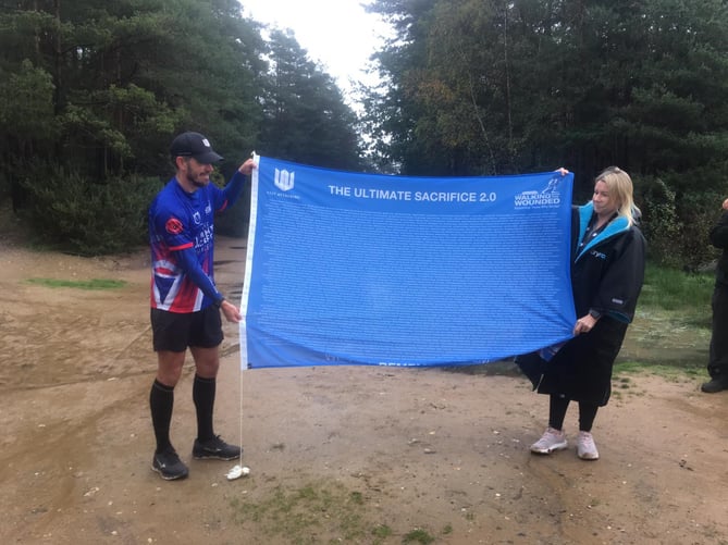 Brian Wood unfurls his Ultimate Sacrifice Challenge flag at the finish of his 35th marathon in 35 days, Hogmoor Inclosure, Bordon, November 7th 2022.