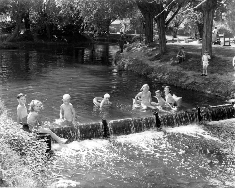 Children splashing around in the slightly deeper waters of Gostrey Meadow in 1957, created by the shallow weir across the river just upstream of the footbridge