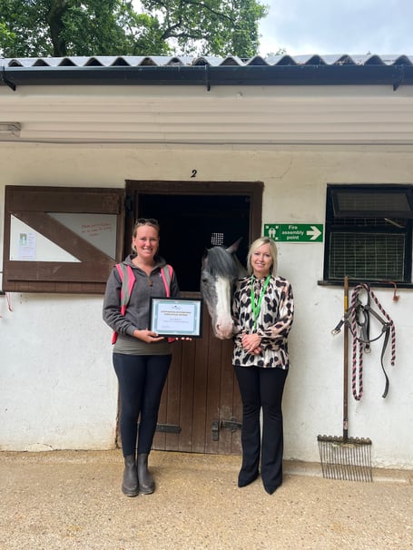 Treloar's supported internship co-ordinator Charlotte Mills presents a certificate to Broadlands Riding for the Disabled in Medstead, July 2023.