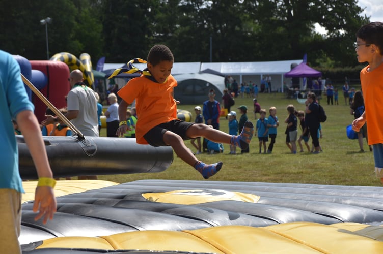 Beavers from Haslemere enjoying the inflatable obstacle course in the summer sunshine