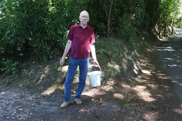 Barry McGerr on Chase Lane with a bucket and teaspoon – a nod to a Thames Water driver’s claim that supplying Haslemere's reservoir is “like filling a bucket with a teaspoon.”