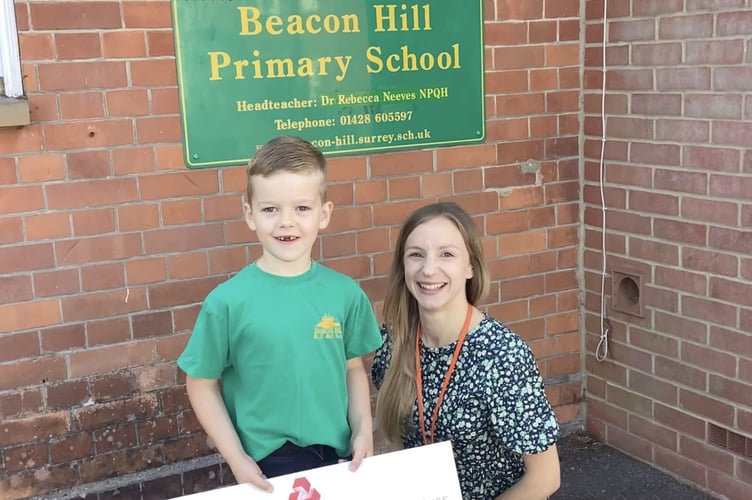 Pupil proudly holds a cheque raised by parents to support outdoor improvements at Beacon Hill Primary School