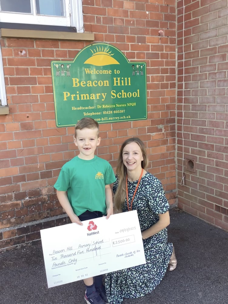 Pupil proudly holds a cheque raised by parents to support outdoor improvements at Beacon Hill Primary School