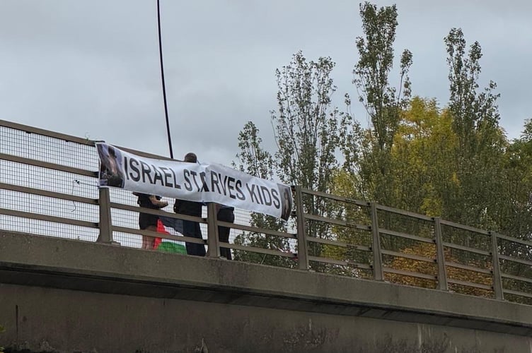 Pro-Palestine activist takes part in a small demonstration in Egham, waving a flag along the M25 bridge