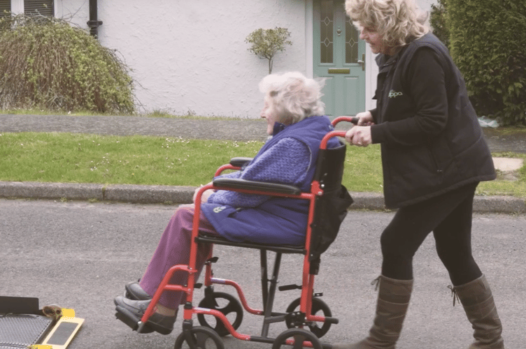 Gail, a regular Hospital Hoppa driver, helping a passenger board the service as the charity highlights the importance of accessible patient transport.